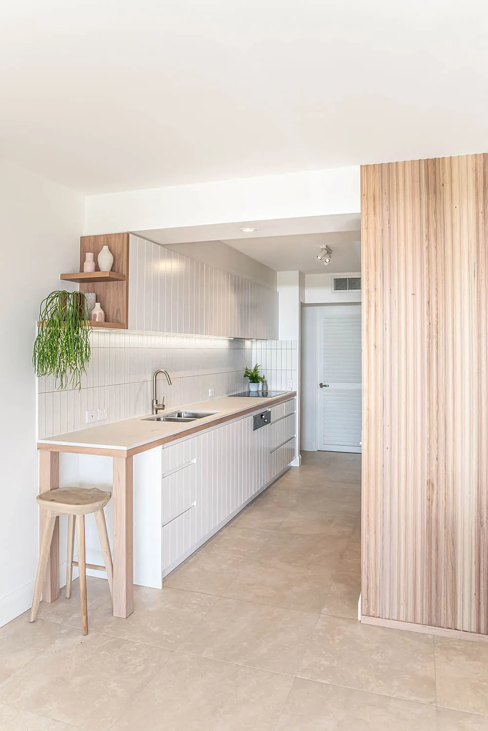 Kitchen with white cabinetry, timber benchtop and vertical timber batten feature