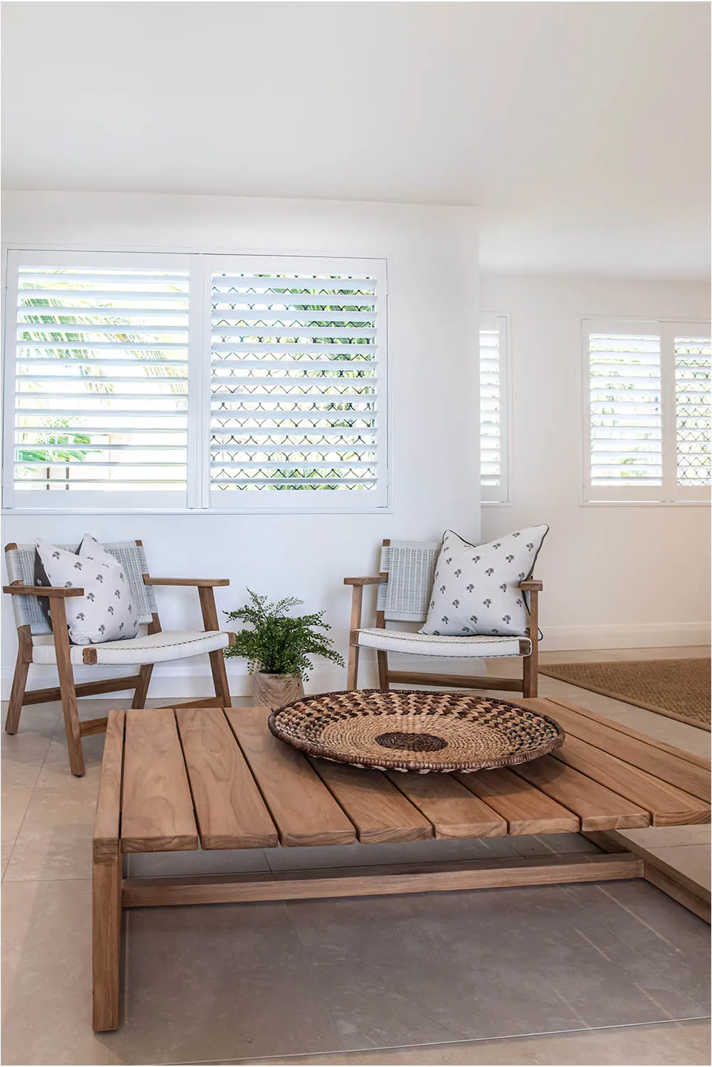 Living area with plantation shutters, timber coffee table and outdoor-style armchairs