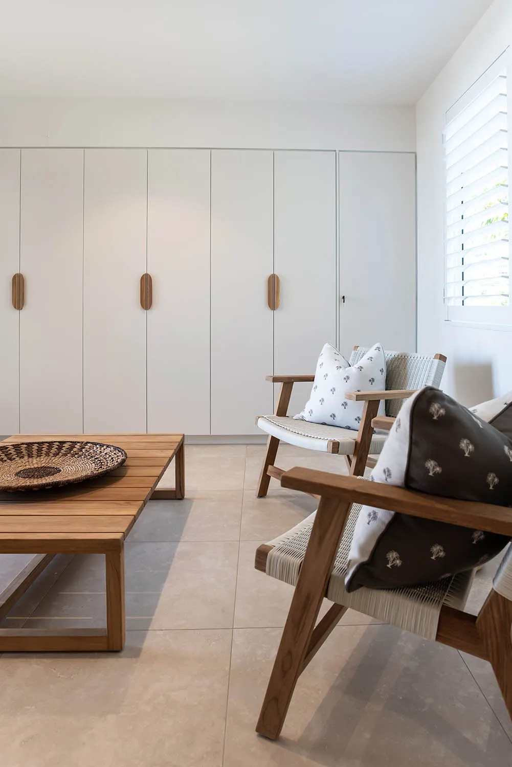 Floor-to-ceiling white built-in wardrobes with timber handles