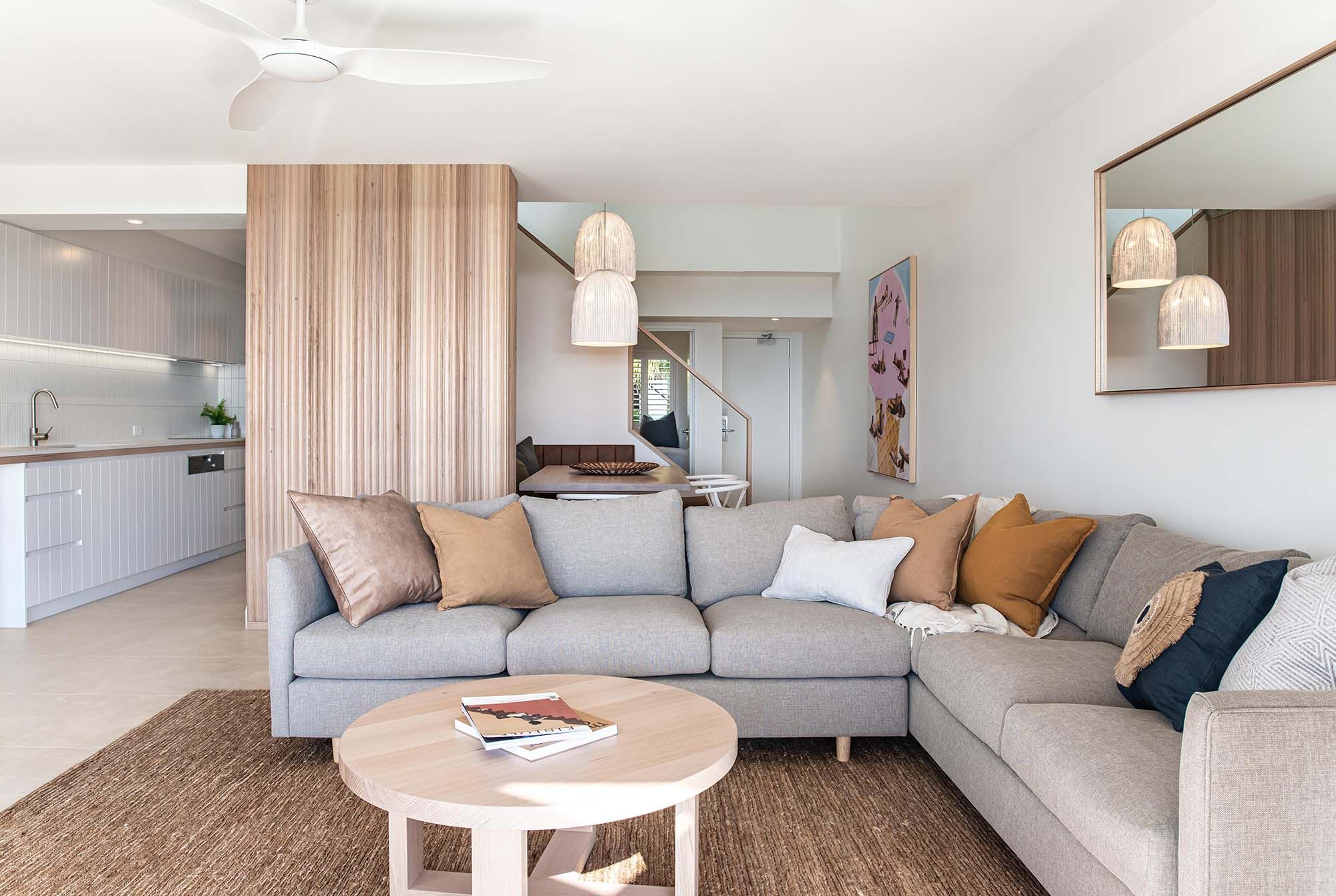 Open-plan living room with a corner sofa, timber batten feature wall and pendant lights